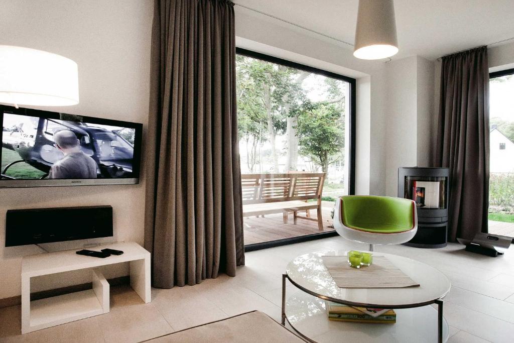 een woonkamer met een televisie en een groene stoel bij die Strandhäuser - Strandläufer in Ostseebad Sellin