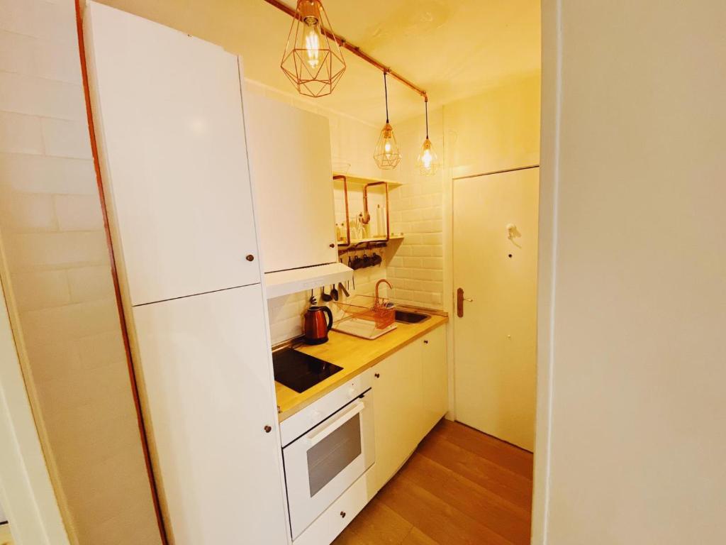 a small kitchen with white cabinets and a white refrigerator at Arena Gold Euroviajeros apartaments in Pineda de Mar