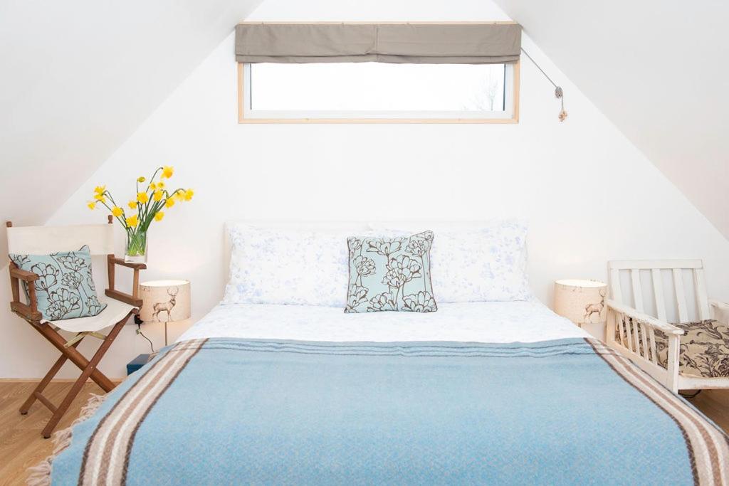 um quarto com uma cama com um cobertor azul e uma janela em The Barn em Chichester