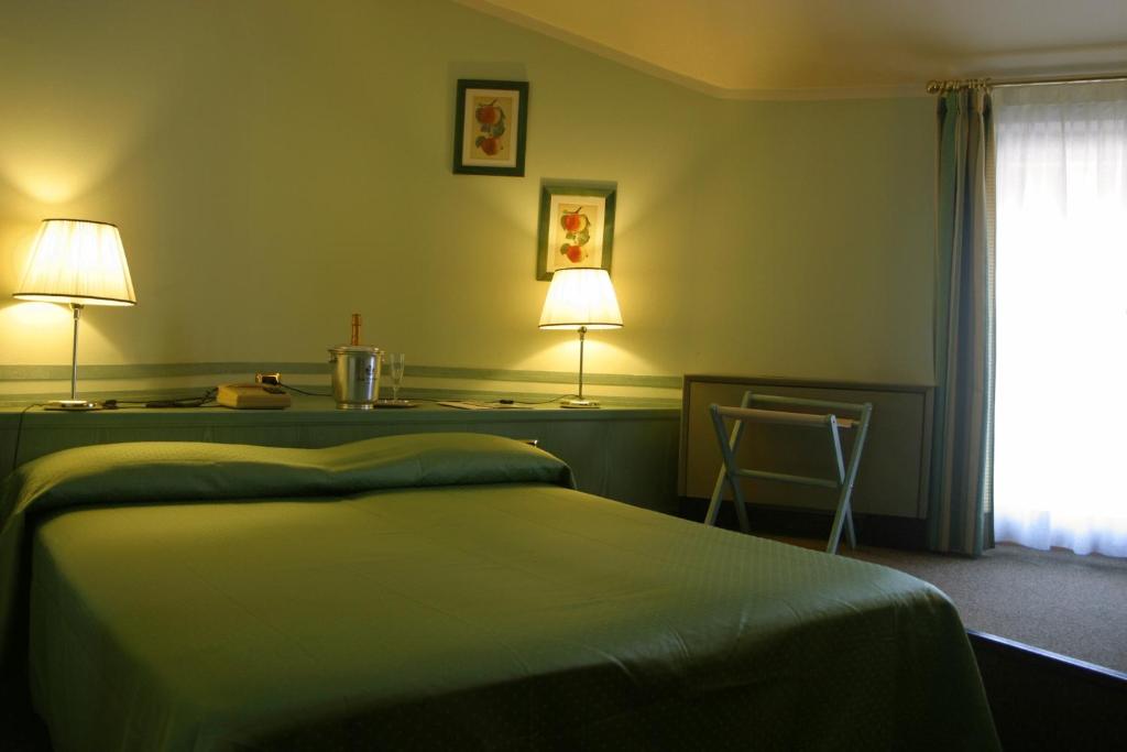 - une chambre verte avec un lit et deux lampes dans l'établissement Albergo Della Corona, à Binasco