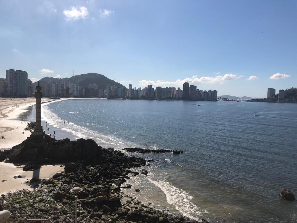 Blick auf einen Strand mit einer Stadt im Hintergrund in der Unterkunft APARTAMENTO FRENTE A PRAIA SAO VICENTE in São Vicente