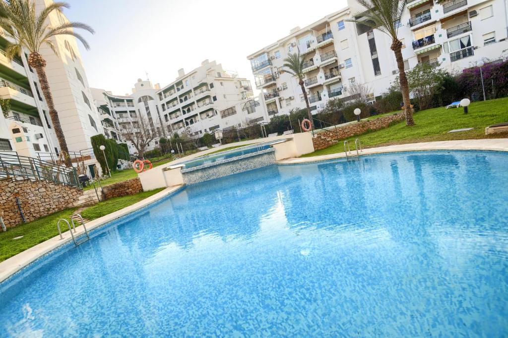 una gran piscina azul con edificios en el fondo en Apartamentos BCL Playa Albir, en Albir