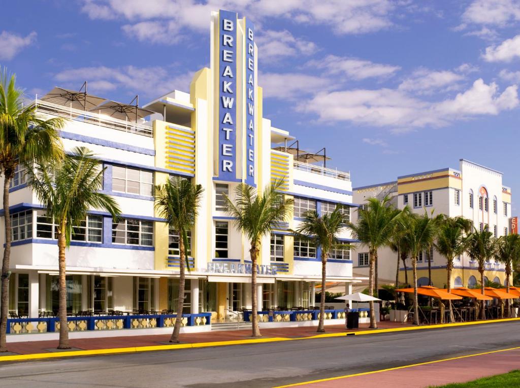 a large white building with palm trees in front of it at Hotel Breakwater South Beach in Miami Beach