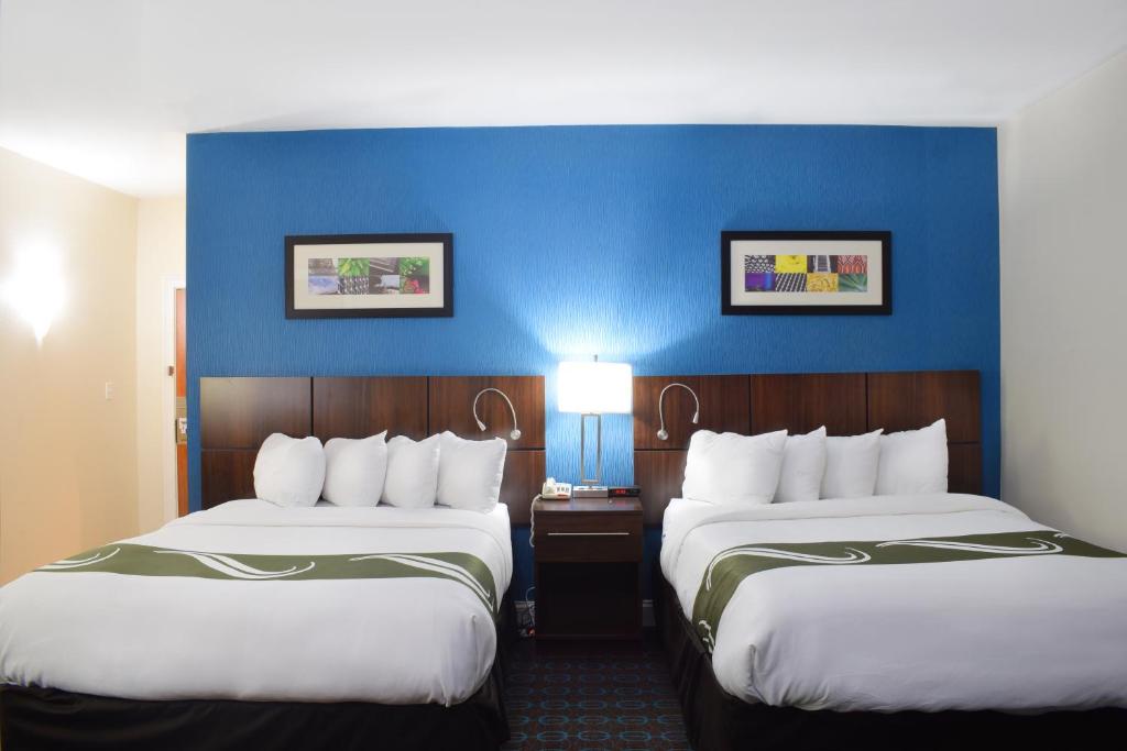 a hotel room with two beds and a blue wall at Quality Inn & Suites Middletown - Newport in Middletown