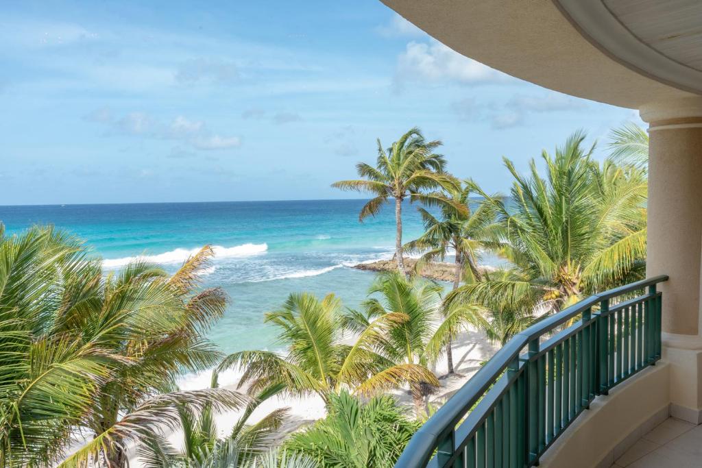 a balcony with palm trees and the ocean at White Sands Beach Condos in Christ Church