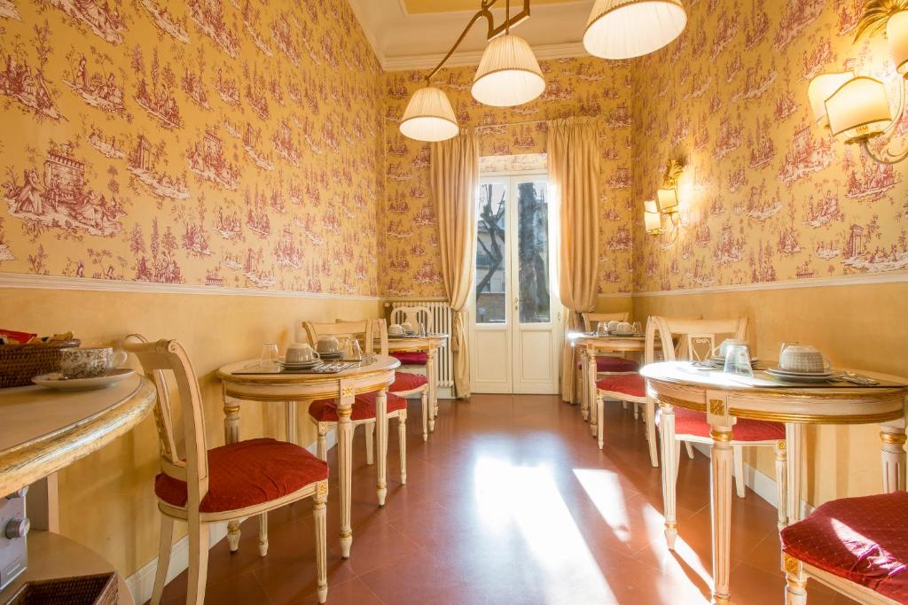 una sala da pranzo con tavoli, sedie e carta da parati di Relais Tiffany a Firenze