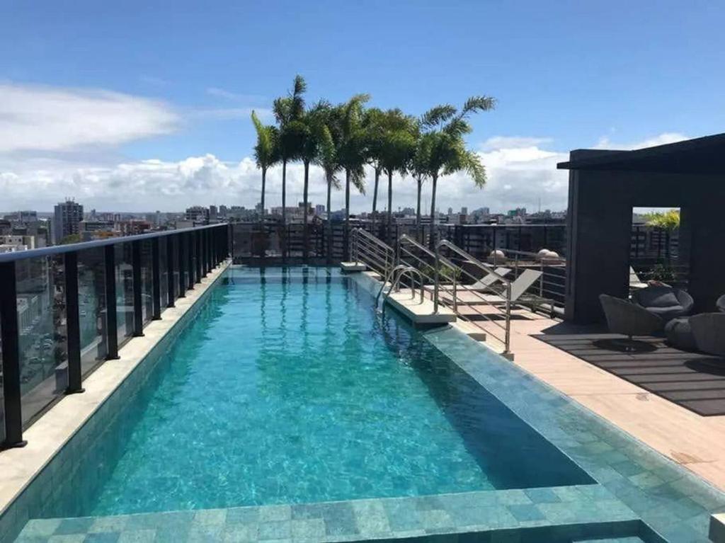 a swimming pool on the roof of a building with palm trees at Confortável studio na Ponta verde in Maceió