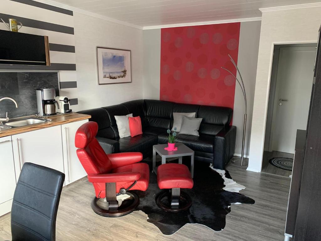 a living room with a black couch and red chairs at Haus-Encore-Wohnung-3 in Büsum