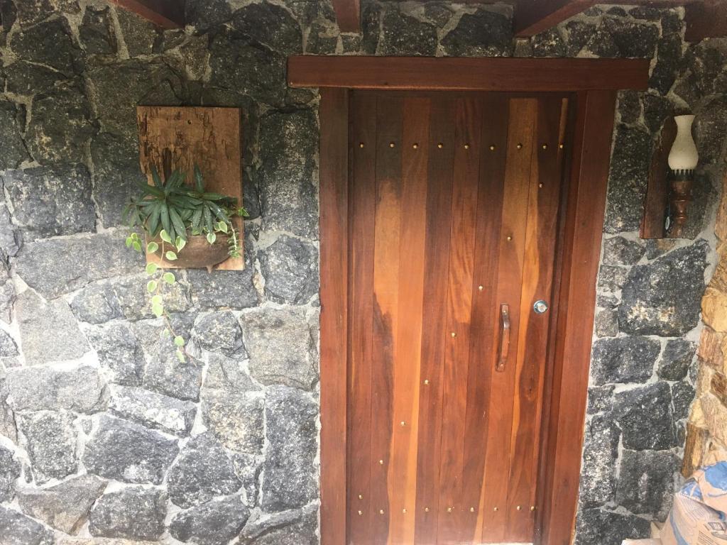 una puerta de madera en una pared de piedra con una maceta en Suíte Cravo & Canela, en São Pedro da Serra