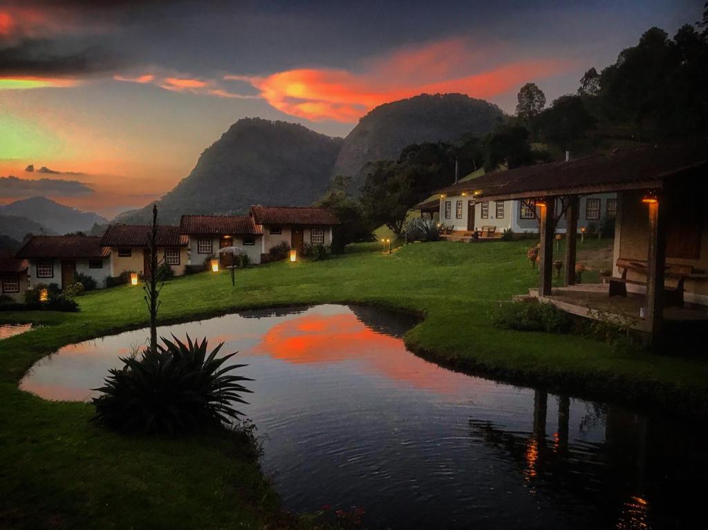 un piccolo stagno in un villaggio con case e montagne di Pousada Gonçalves a Gonçalves