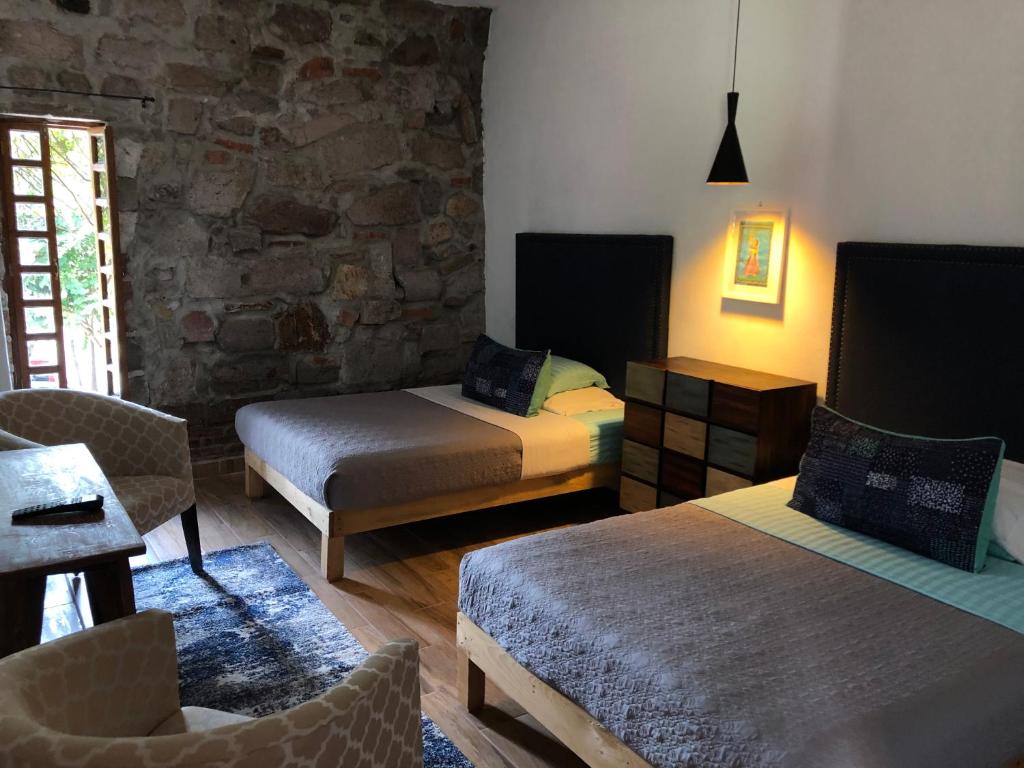 Hotel Real de Piedra في Pénjamo: غرفة نوم بسريرين وجدار حجري