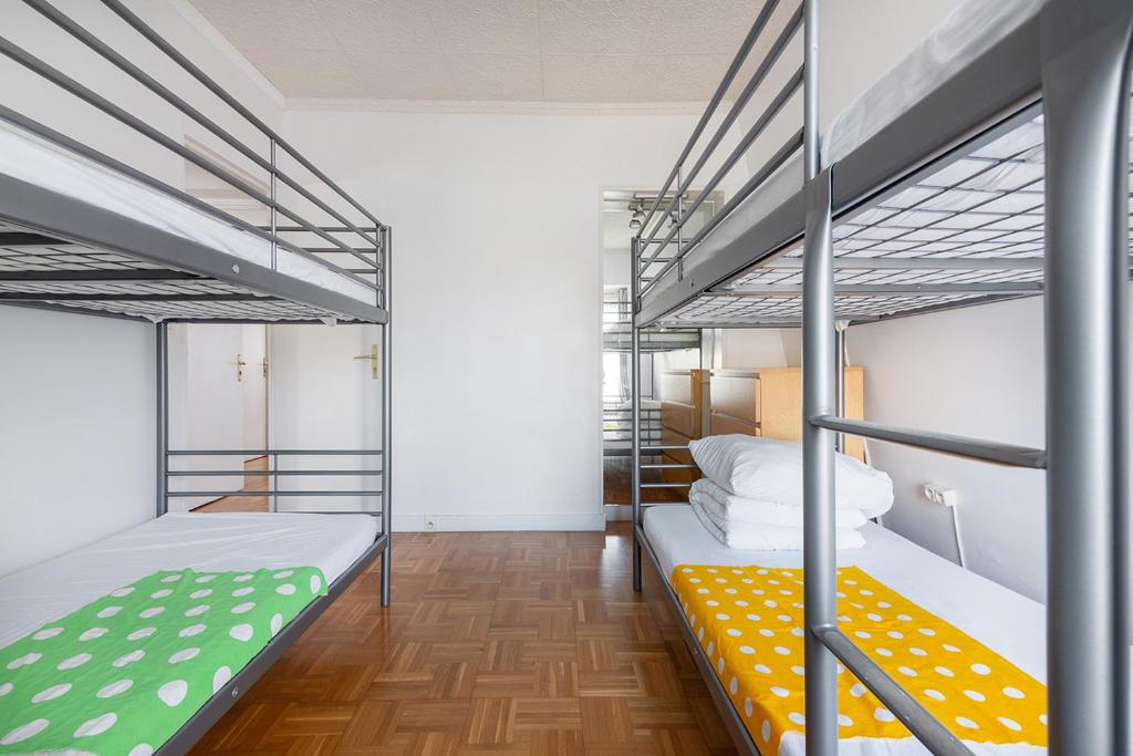 a room with two bunk beds and wooden floors at Cameleon Paris Guesthouse in Pantin