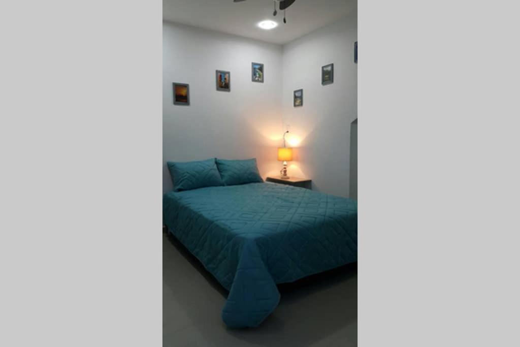 1 dormitorio con 1 cama azul y 1 lámpara en Habitación Privada 10 min de la playa, entrada independiente., en Santa Marta