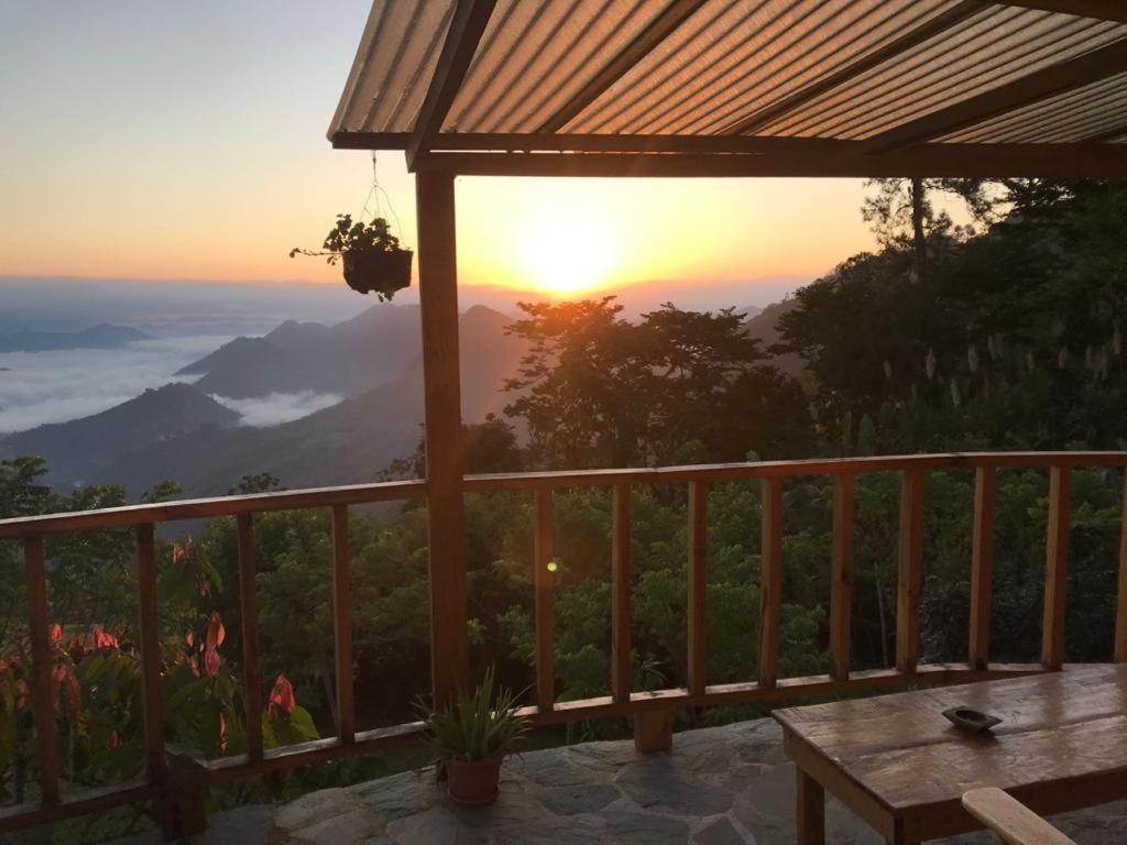 a view of the sunset from a deck with a table at Mountain Nest in Lanquín