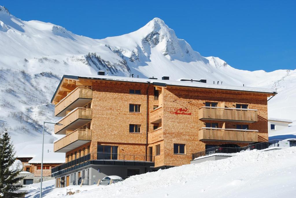 budynek na szczycie pokrytej śniegiem góry w obiekcie Alphof Appartement Faschina w mieście Fontanella
