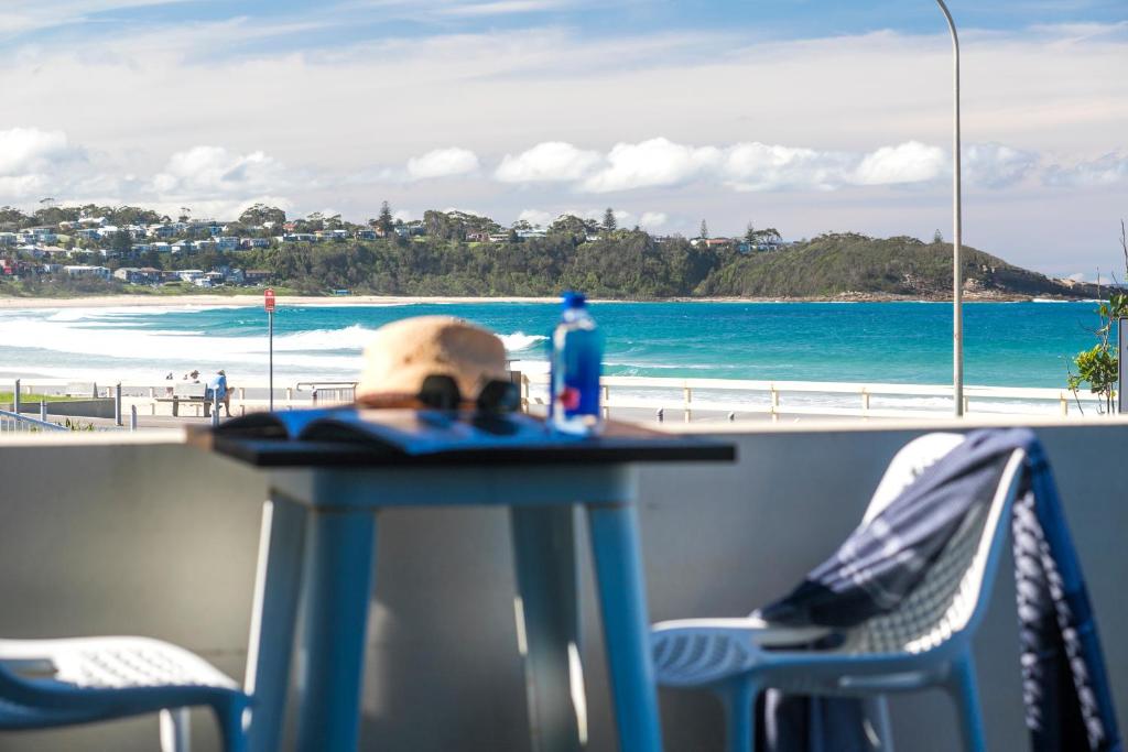 een tafel met stoelen en uitzicht op het strand bij Beachfront One, Mollymook in Mollymook