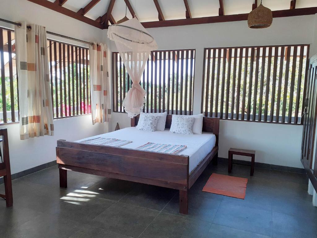 a bedroom with a bed in a room with windows at East Surf Cabanas in Arugam Bay