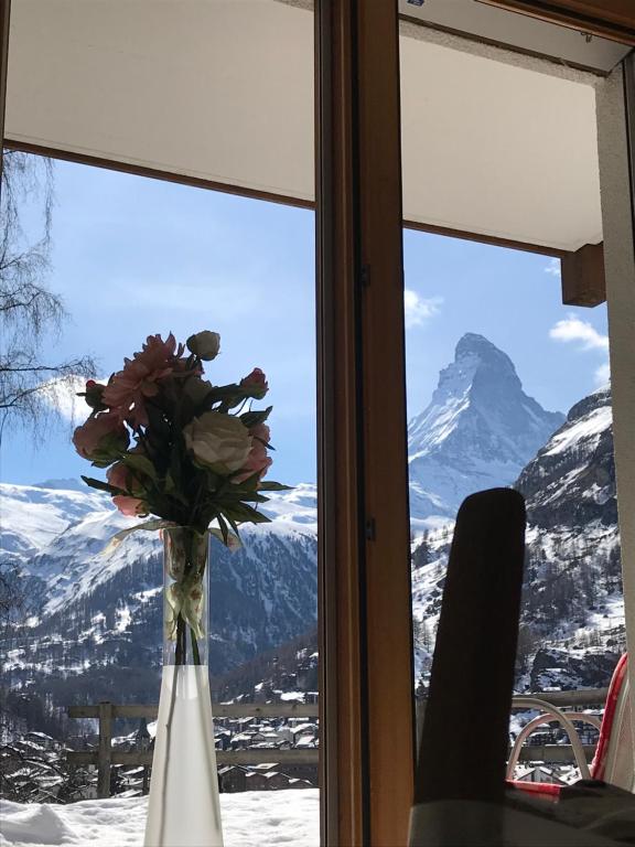 a vase of flowers in a window with a mountain view at Millennium in Zermatt