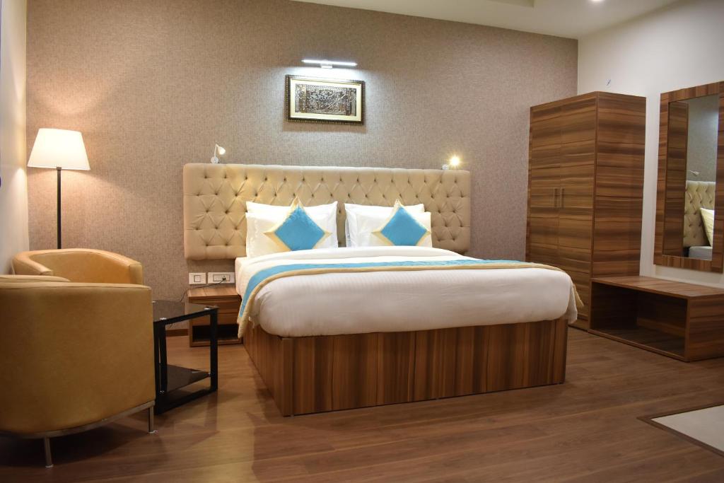 a hotel room with a large bed and a chair at The Grand Hotel, Muzaffarpur in Muzaffarpur