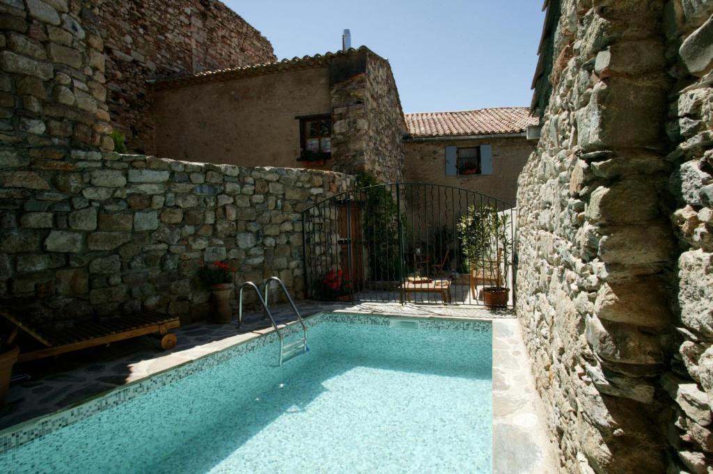 una piscina frente a un edificio de piedra en La piscine de tonton Jean en Caunes-Minervois