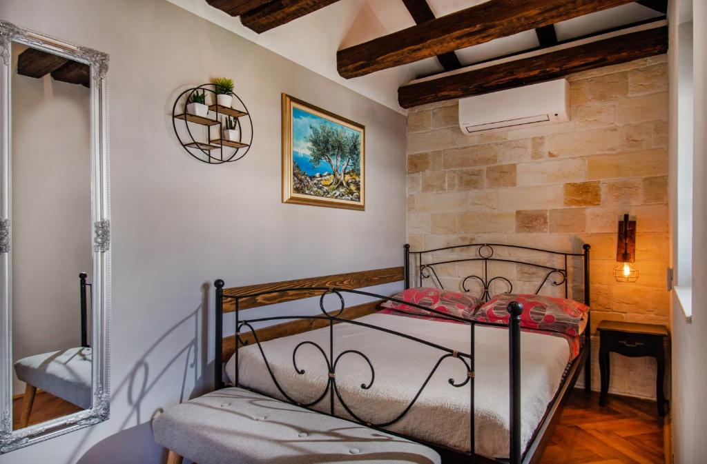 een slaapkamer met een metalen bed en een stenen muur bij Apartment Ami in Split