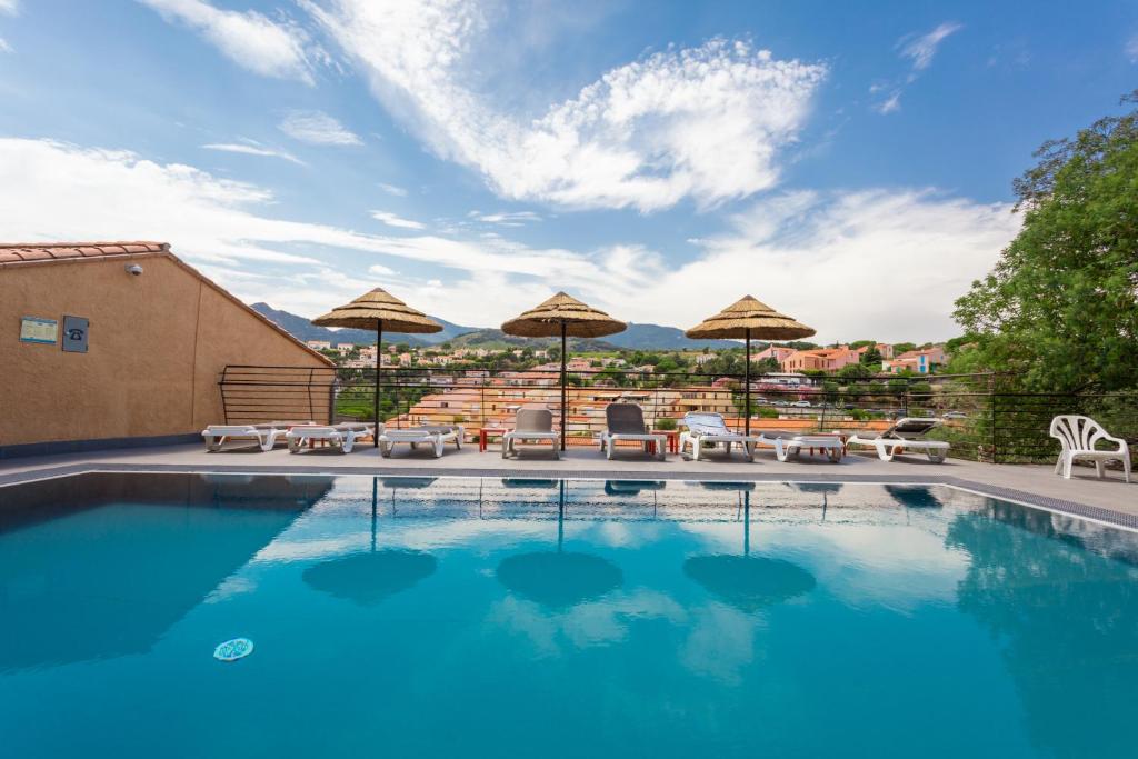 una piscina con muebles de exterior y sombrillas en Le Madeloc Hôtel & Spa, en Collioure