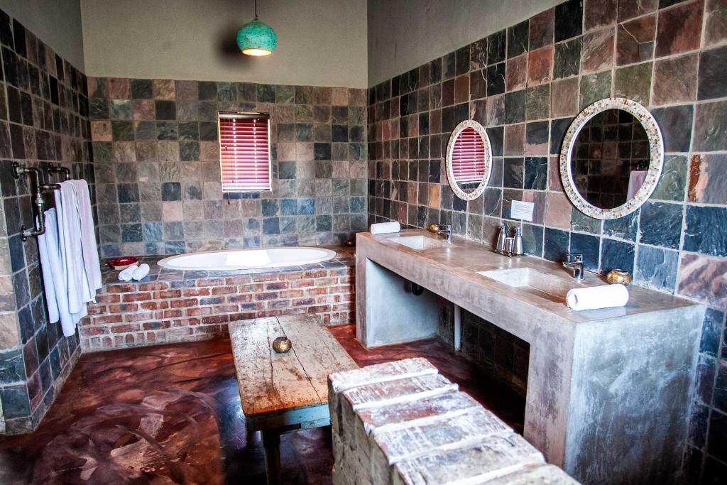 een badkamer met 2 wastafels, een bad en een bad bij Rustique Boutique Hotel in Middelburg