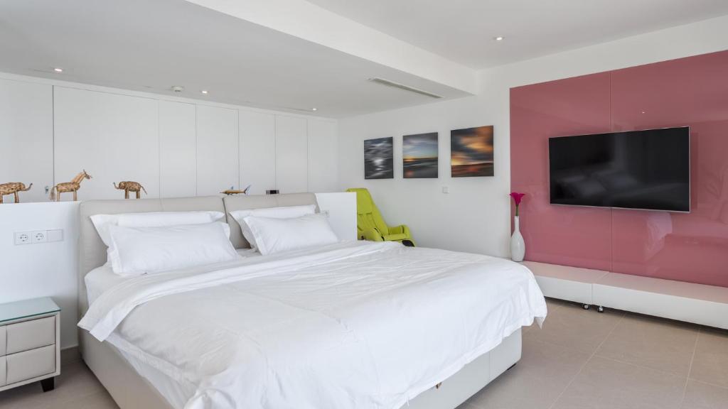 a white bedroom with a large bed and a tv at The Hype Beachhouse in Playa de Palma