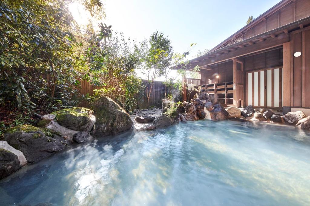 una piscina de agua frente a una casa en Ryokan Ichinoi, en Minamioguni