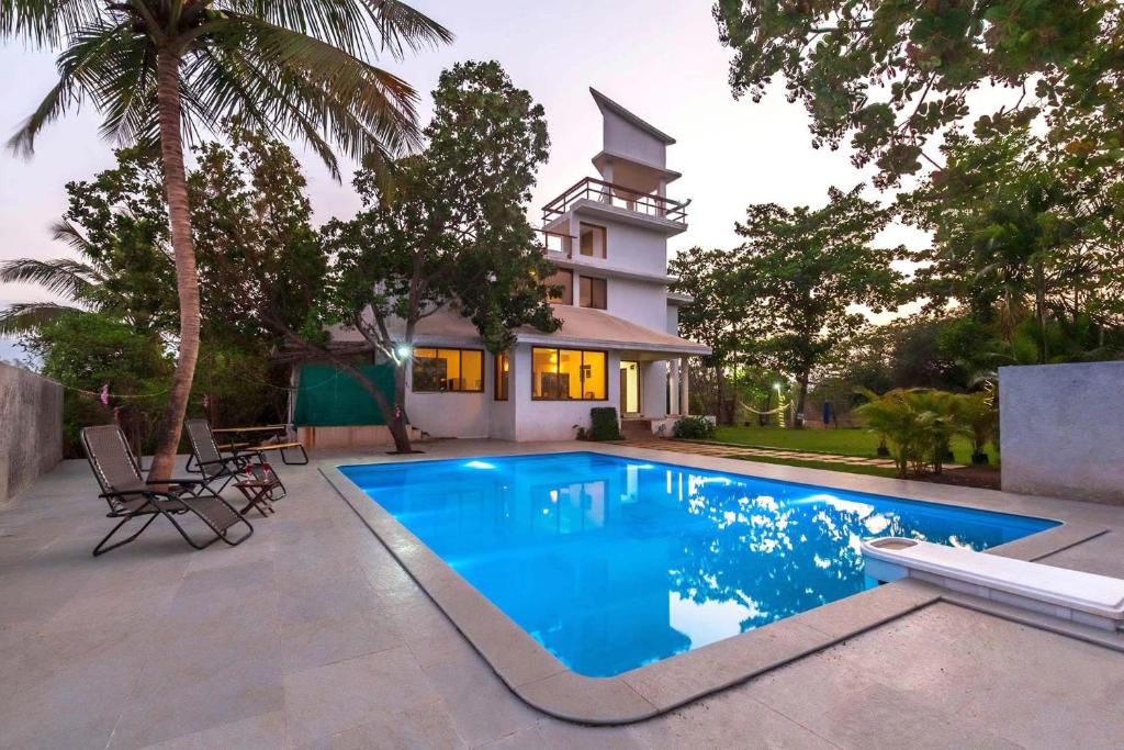 a swimming pool in front of a house at StayVista's Santoni Farms - Riverside Bliss with Pool, Orchard & Activities in Karjat