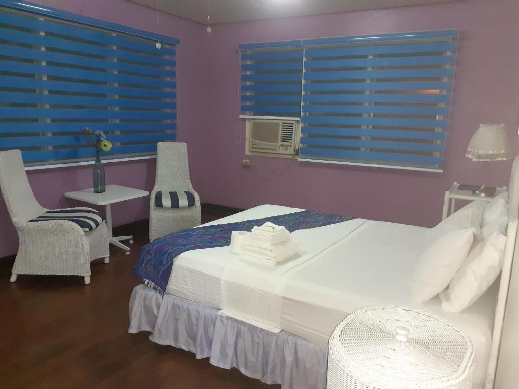 a bedroom with a bed and chairs and blue windows at Casa Joaquin BnB in Manila