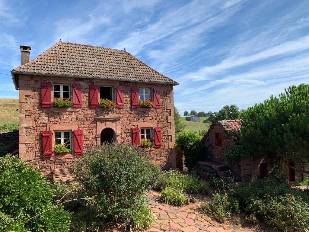 Une vieille maison en pierre avec des volets rouges dans l'établissement La douce France, à Collonges