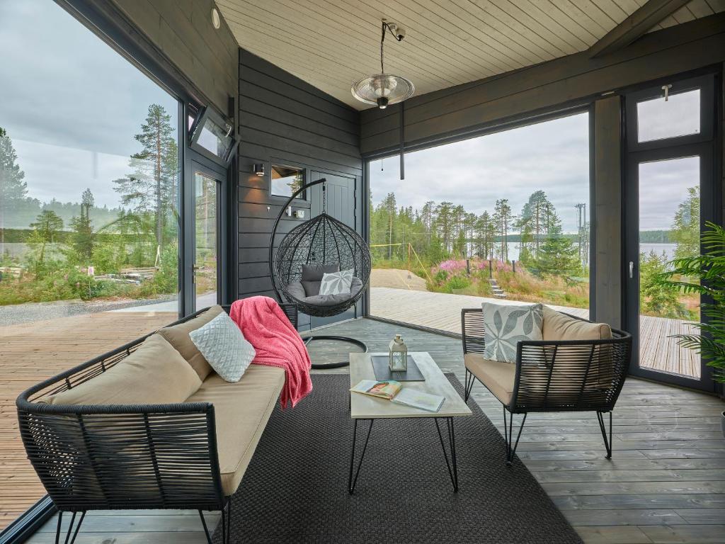 a screened in porch with a couch and chairs at Huvila erämaajärven rannalla Taivalkoskella in Jokijärvi