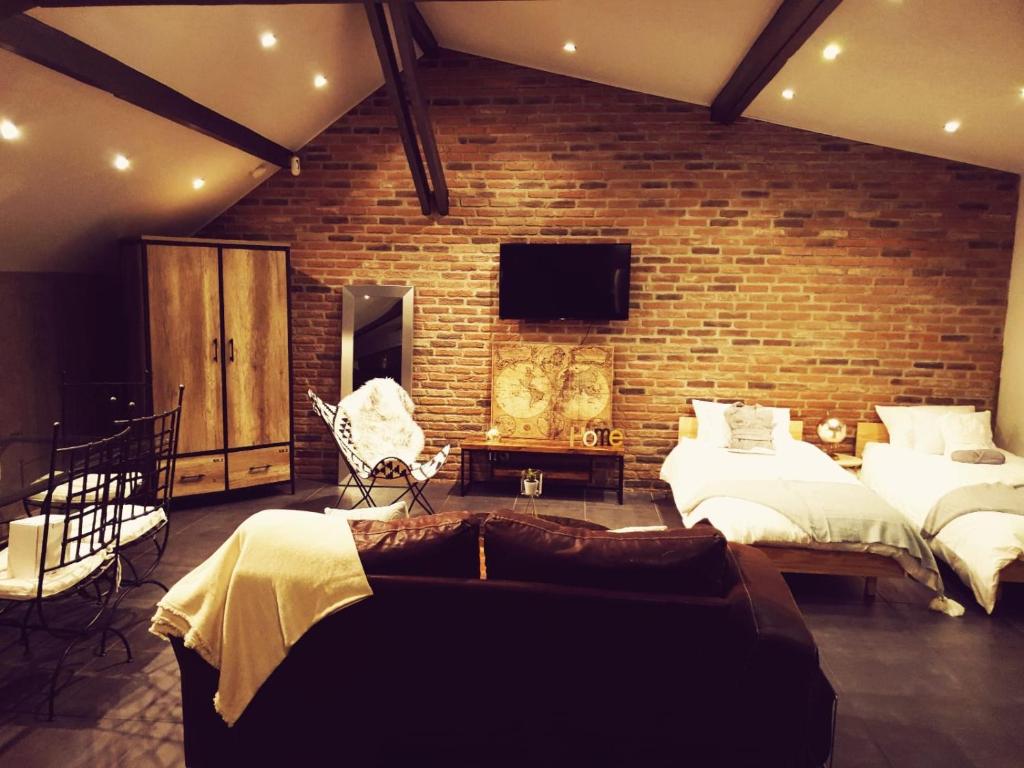 a bedroom with two beds and a brick wall at Le Loft in Aulnay-sous-Bois