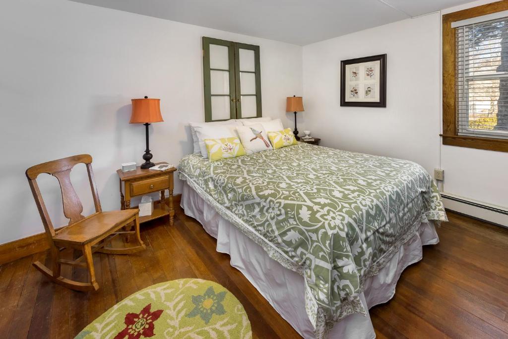 a bedroom with a bed and a chair and a window at The Craignair Inn & Causeway Restaurant in Spruce Head