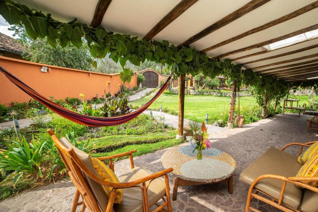 un patio con un'amaca, un tavolo e delle sedie di Andean Wings Valley a Urubamba