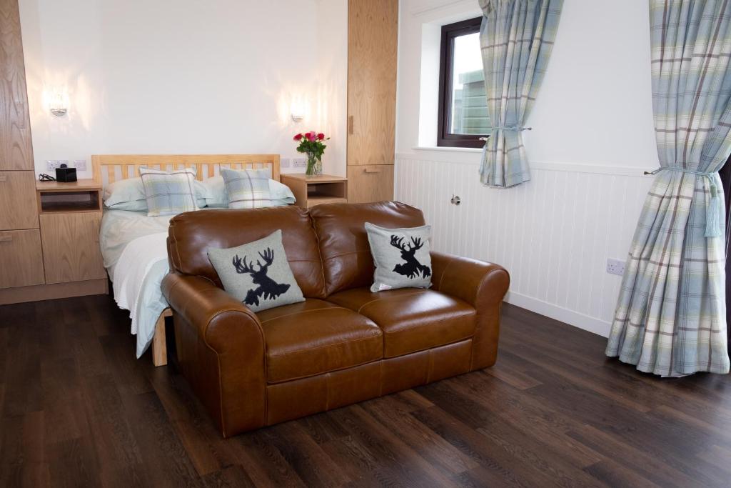 a bedroom with a bed and a brown leather couch at Drumossie Bothy in Inverness
