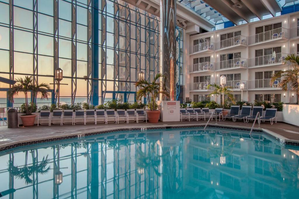 uma piscina em termia de um hotel com cadeiras e um edifício em Princess Royale Oceanfront Resort em Ocean City