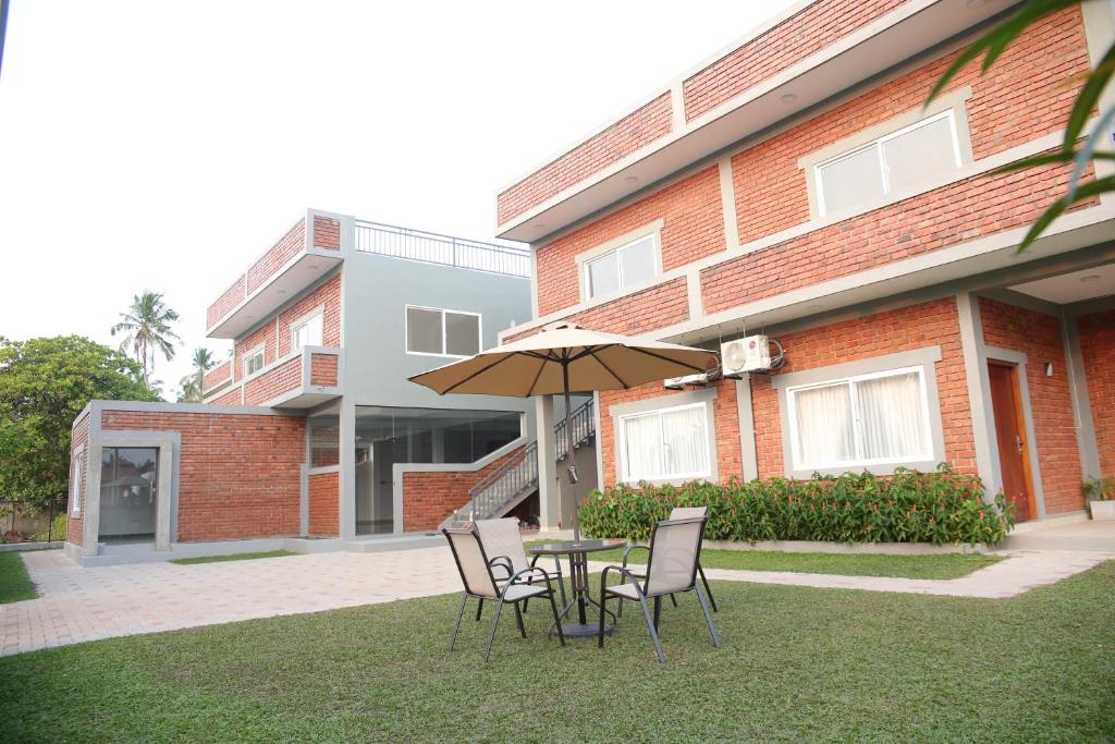 a table and chairs with an umbrella in front of a building at Amadel Negombo in Negombo
