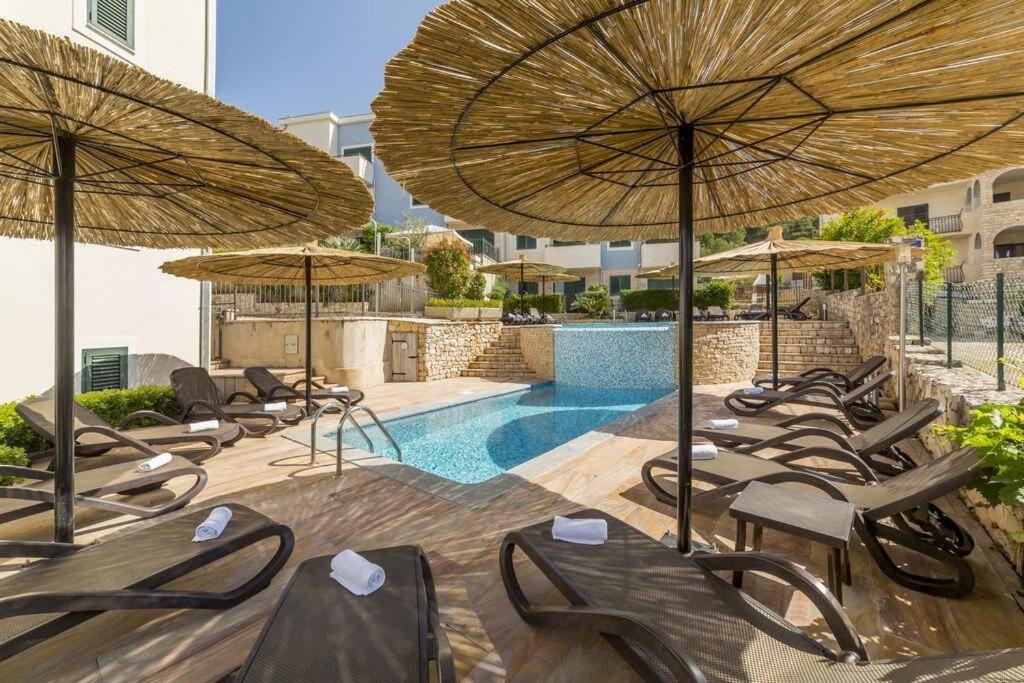 a group of chairs and umbrellas next to a pool at SeaEsta apartment Pool and Beach in Slatine