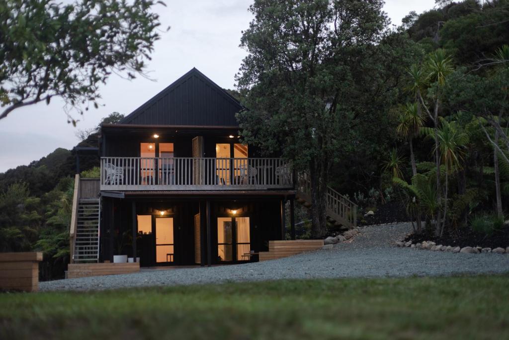 a house with a balcony on the side of it at Tui & Nikau Cabins in Mangawhai