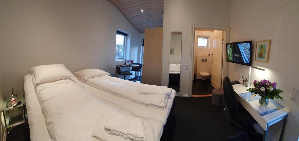 um quarto com uma cama branca num quarto em Bente's Guesthouse em Holstebro