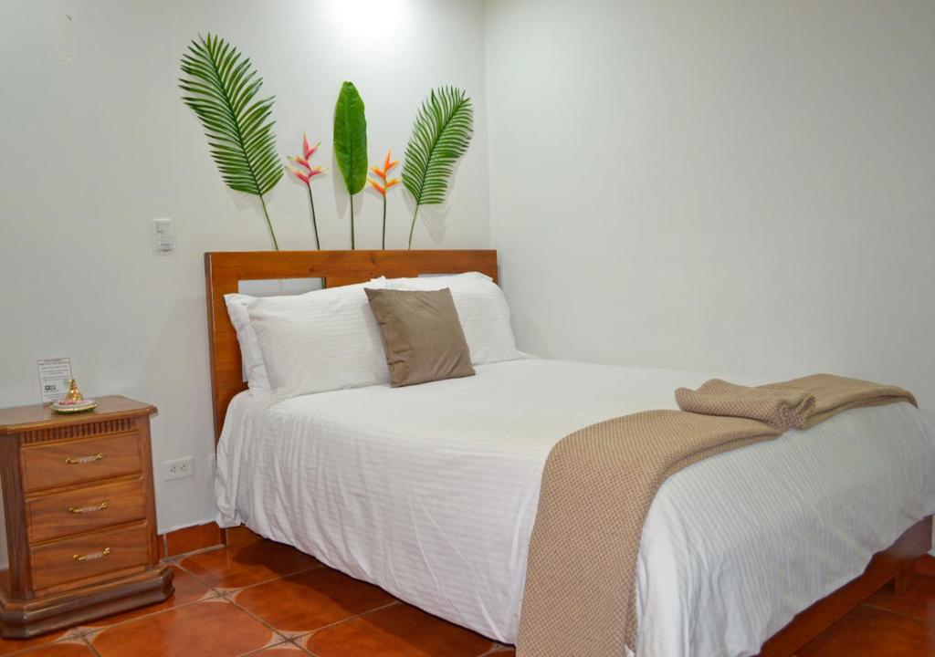 1 dormitorio con 1 cama y 2 plantas en la pared en Casa Tropical en San Joaquín