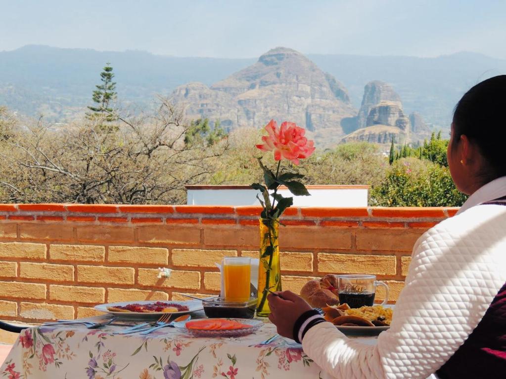 una mujer sentada en una mesa con un plato de comida en Hotel Boutique Jardín de Flores, en Tlayacapan