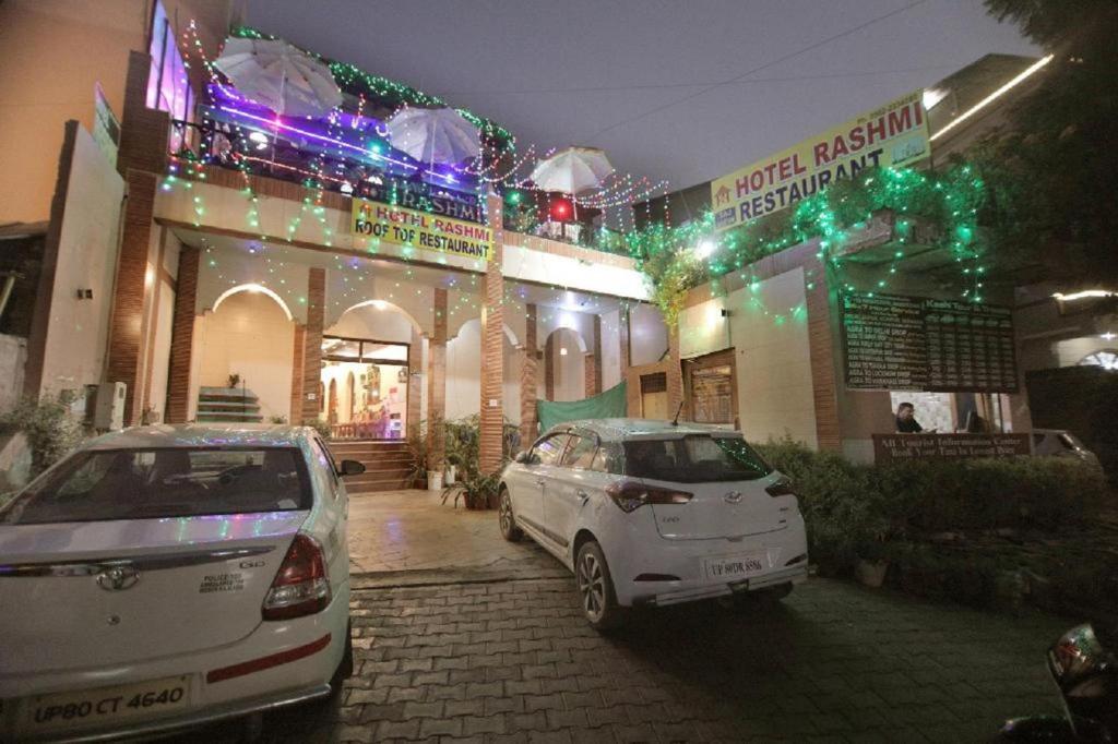 deux voitures garées devant un bâtiment aux lumières de Noël dans l'établissement Hotel Rashmi, à Agra