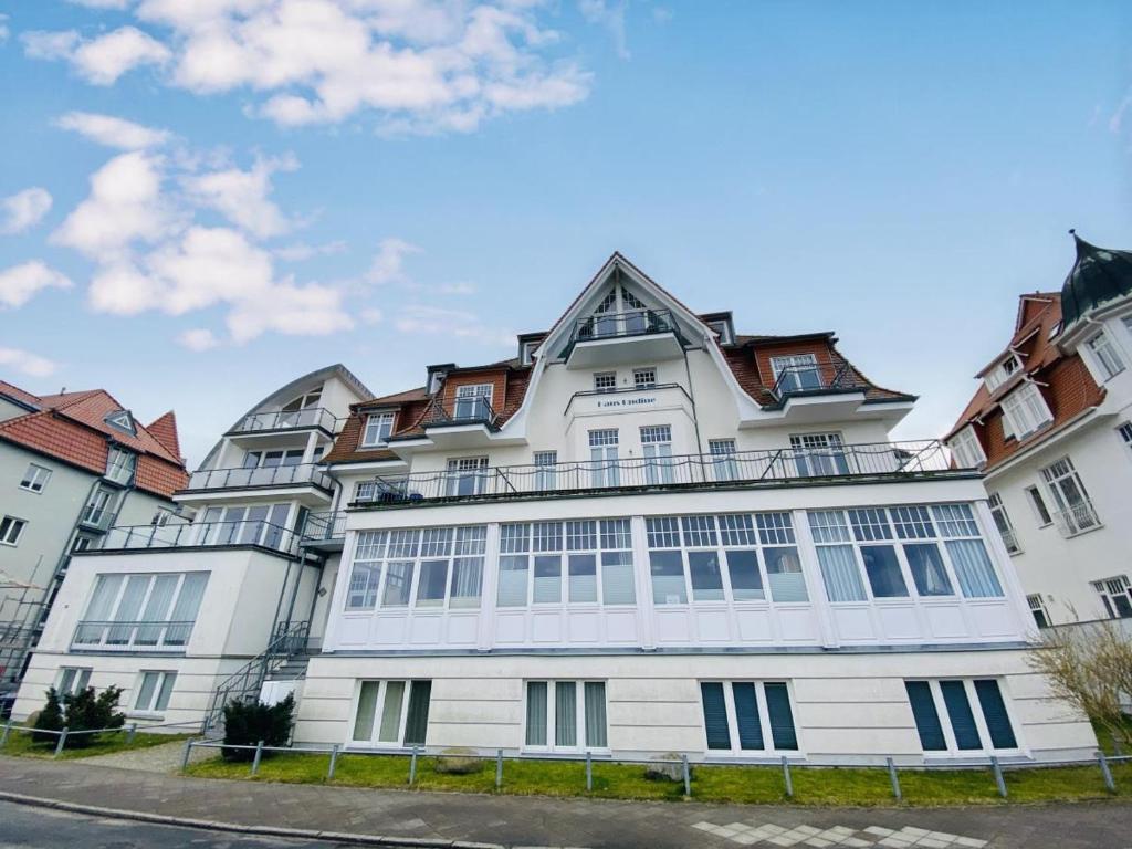 Un grand bâtiment blanc avec des fenêtres donne sur une rue. dans l'établissement Achterdeck, direkt an der Promenade, à Warnemünde