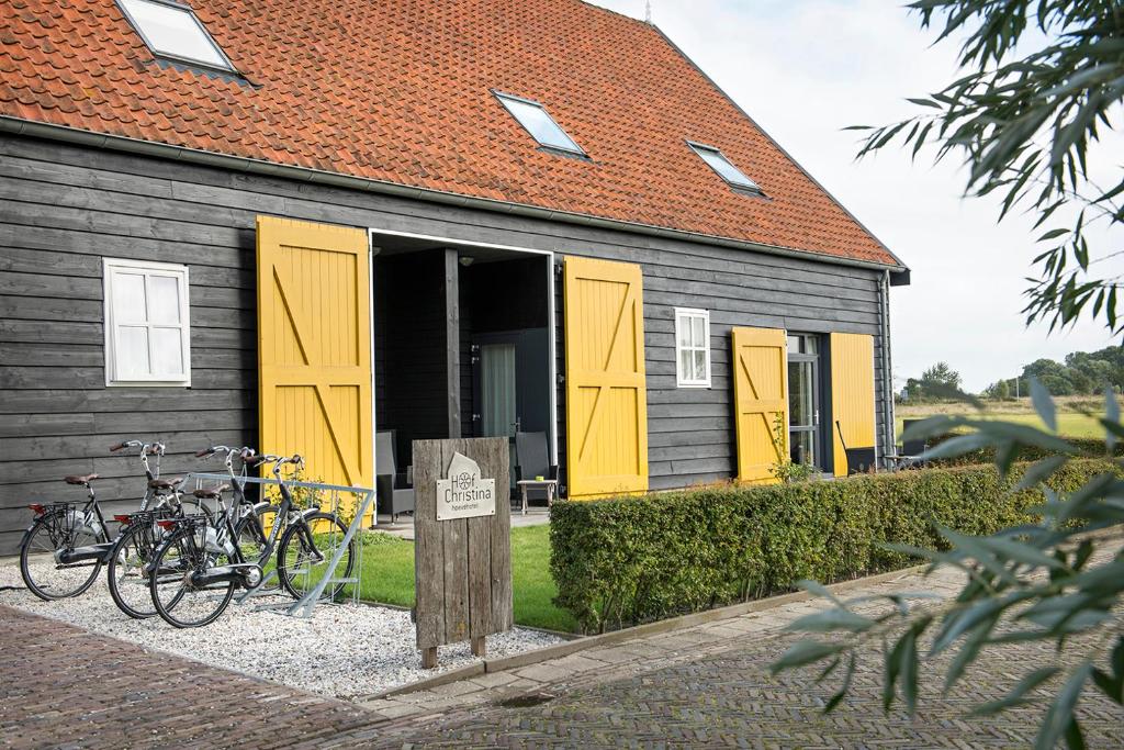 een gebouw met gele deuren en buiten geparkeerde fietsen bij Hoevehotel 'Hof Christina' in Vrouwenpolder