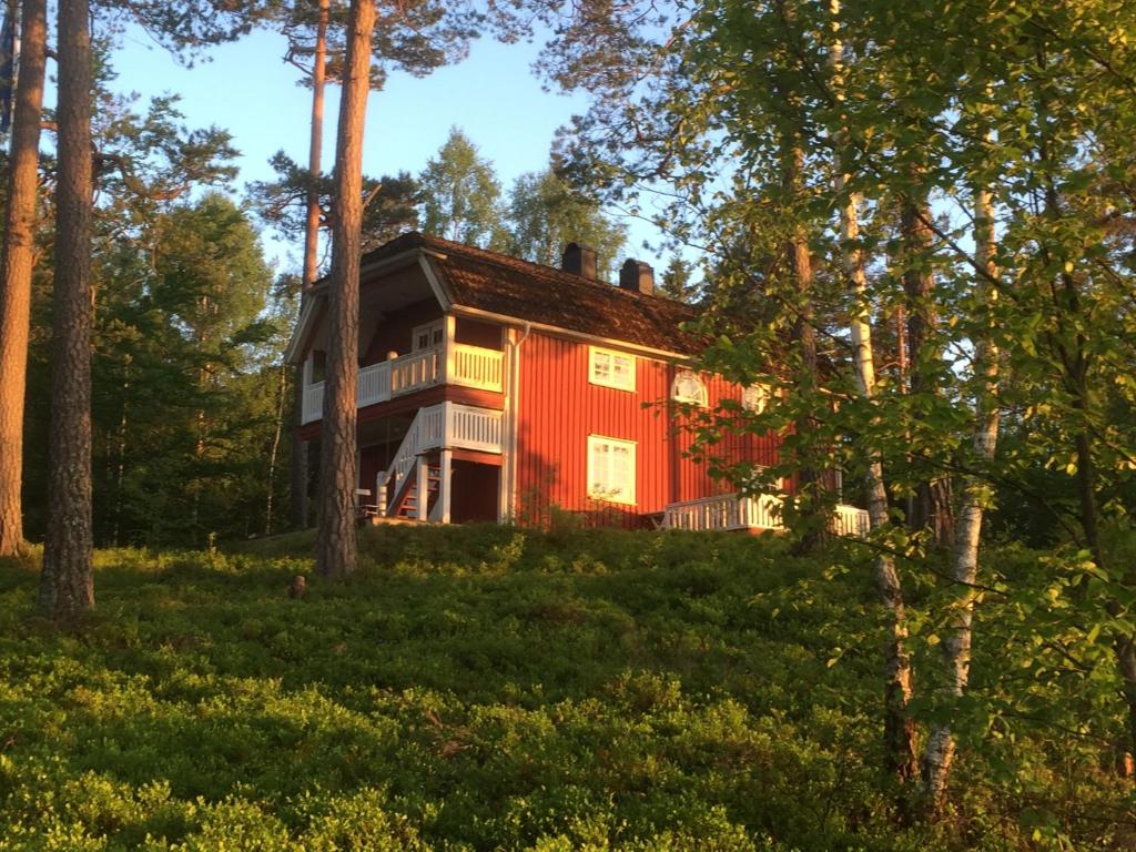 una casa roja en el bosque con árboles en Skyarp Villan, en Håcksvik
