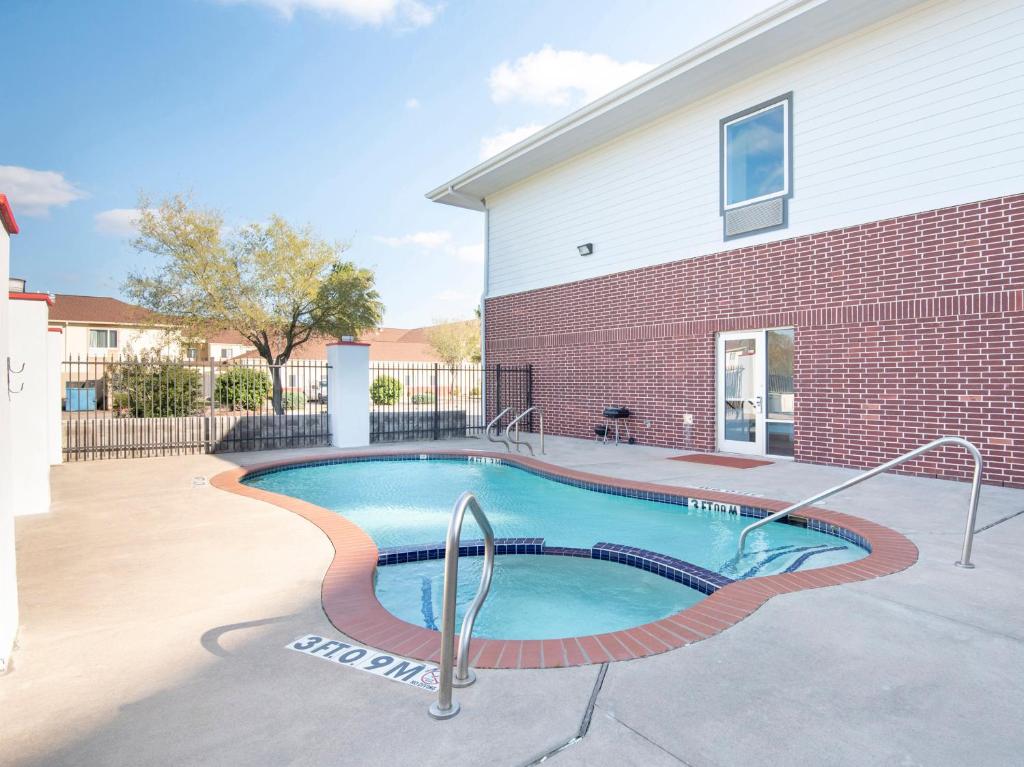 a swimming pool in front of a brick building at OYO Townhouse Clute Lake Jackson in Clute