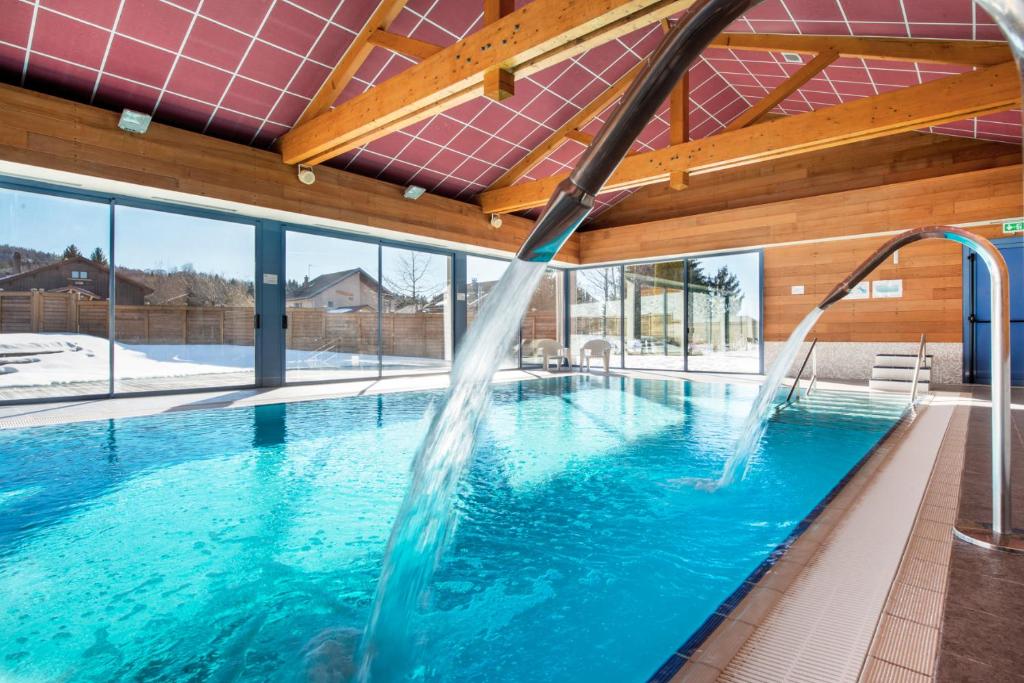 a swimming pool with water shooting into the air at Village vacances Chalet de la Haute-Joux in Cerniébaud